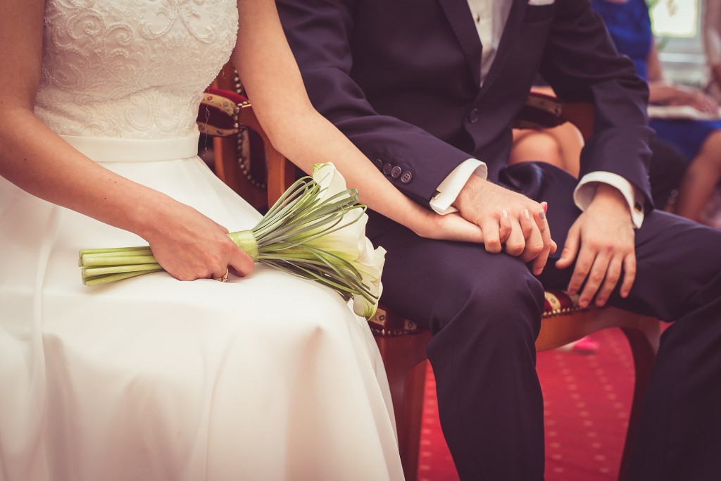 Bride and Groom seated hold hands