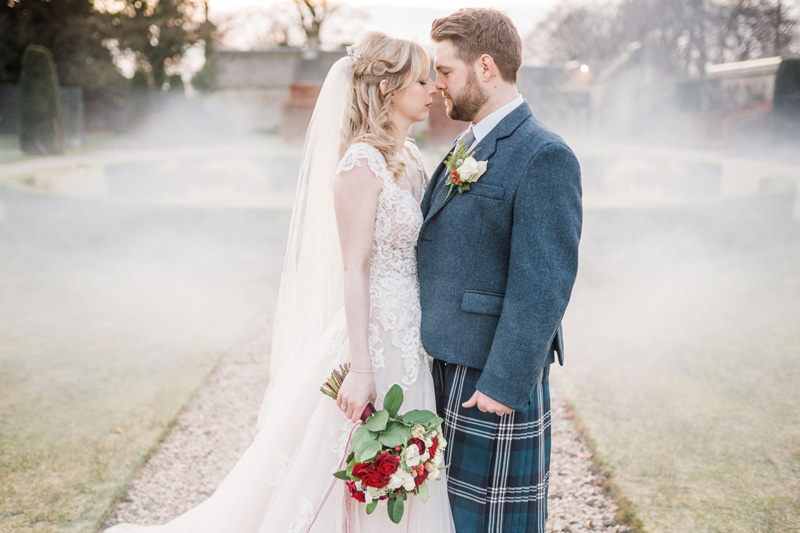 Bride and Groom stand outside Carlowrie Castle wedding in mist