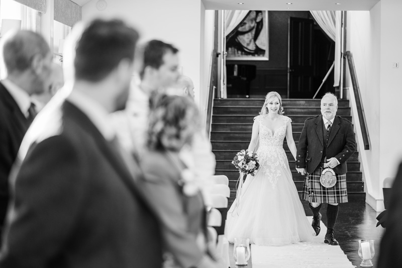 Bride walking down the aisle with Father Carlowrie Castle wedding