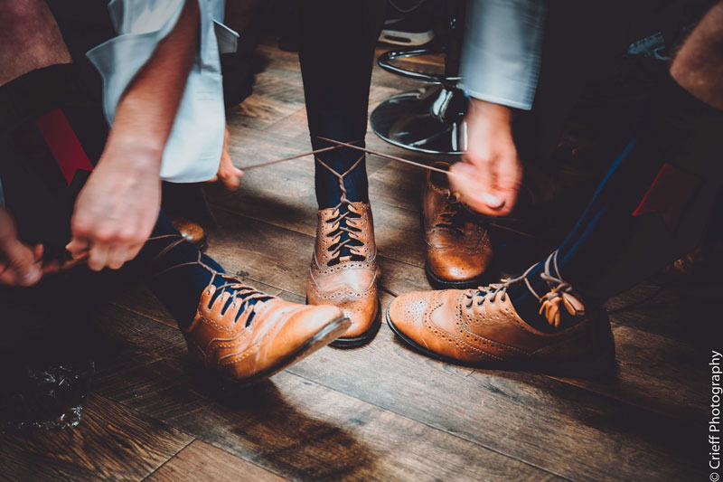 Groomsmen tie laces on Ghillie Brogues at Comrie Croft