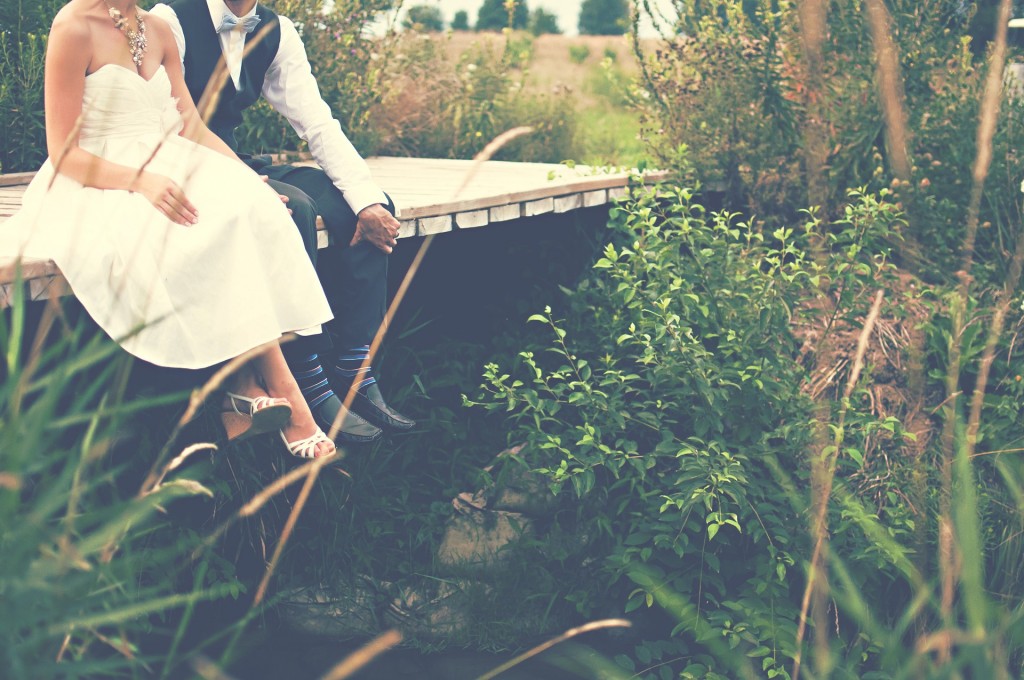 Bride and Groom sit on bridge over stream