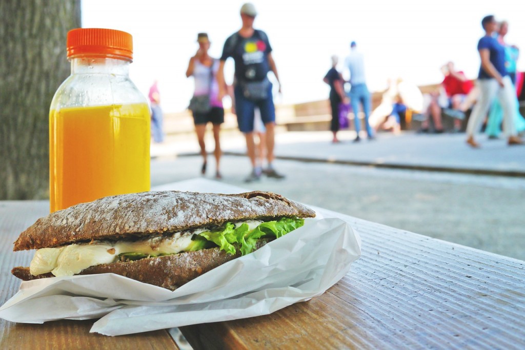 Sandwhich on bench as people walk by