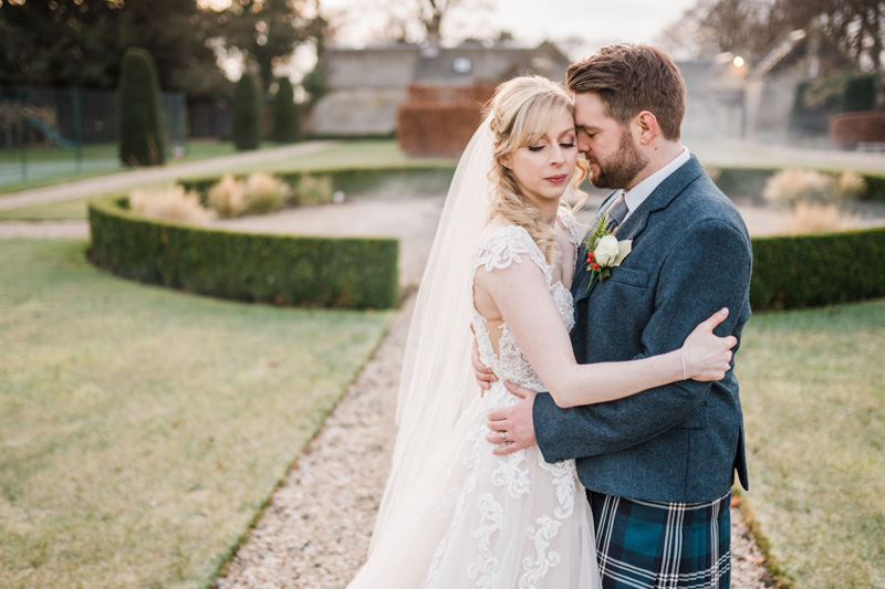 Bride and Groom embrace in gardens Carlowrie Castle Edinburgh