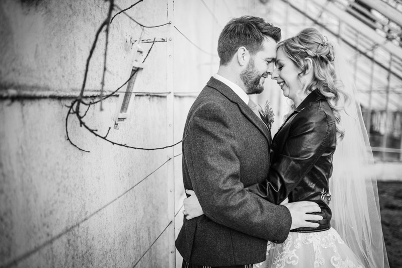 Bride and Groom embrace in gardens of Carlowrie Castle