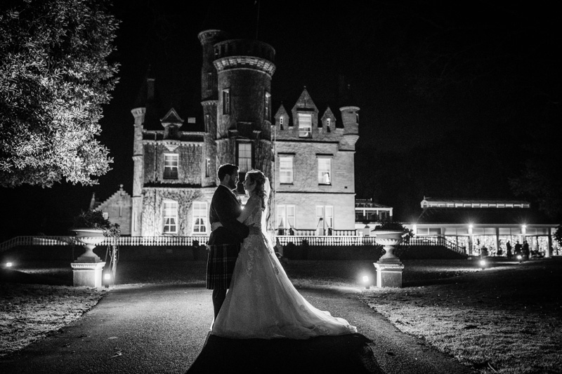 Bride and Groom stand outside Carlowrie Castle night black and white